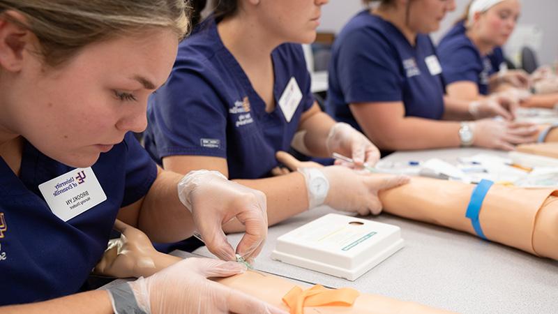 Nursing students practicing injections into fake arms